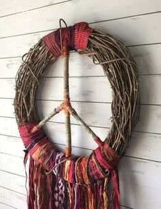 a peace sign made out of twigs and yarn hanging on a wall with a twig