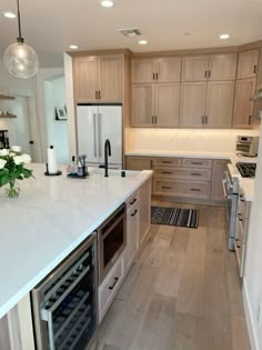 a kitchen with white counter tops and wooden flooring next to a wine cooler in the center