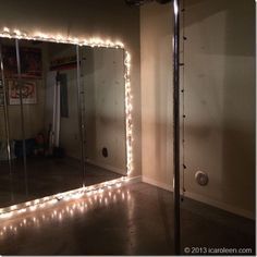 a large mirror with lights on it in a room next to a wall and door