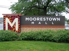 the sign for mooretown mall is shown in front of some bushes and trees,