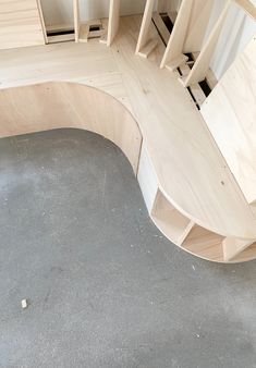 a curved wooden bench sitting on top of a cement floor