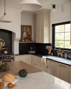 a kitchen with marble counter tops and white cabinets, along with a painting on the wall