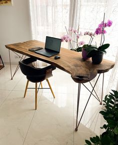 a laptop computer sitting on top of a wooden desk next to a potted plant