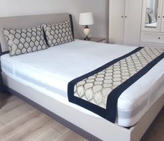 a bed with white sheets and pillows in a room