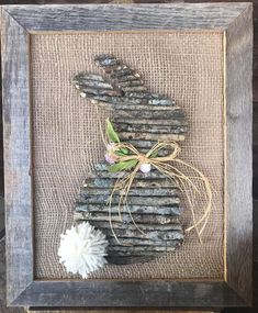 a wooden frame with a bunny made out of sticks and flowers on top of it