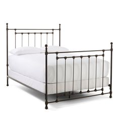 an iron bed frame with white sheets and pillows