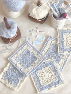 several crocheted squares are sitting on a table with yarn, scissors and thread