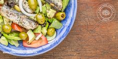 a blue and white bowl filled with salad on top of a wooden table