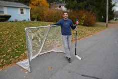 a man standing next to a net holding a hockey stick