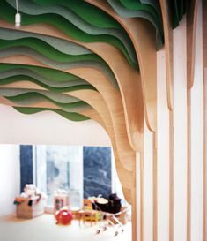 the interior of a building with wooden slats and green wavy designs on the ceiling