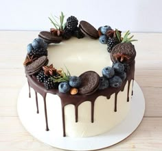 a white cake topped with chocolate cookies and blueberries on top of a wooden table