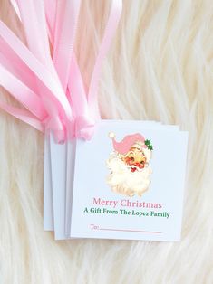 a christmas card with a pink ribbon attached to it on top of a fur surface