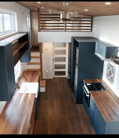 the interior of a tiny house with wood flooring and white walls, stairs leading up to an upper level loft