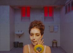 a woman holding a yellow object in front of her face with white clay on it