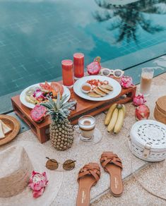 a table with food and drinks near a swimming pool