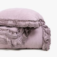 two pillows stacked on top of each other with ruffled edges and one pillow folded down