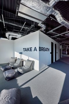 an office with couches and chairs in the middle of it, next to a wall that says take a breath