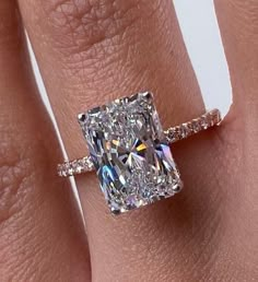 a woman's engagement ring with a cushion cut diamond in the center and pave band