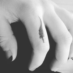 a person's hand with a small feather tattoo on their left thumb and finger