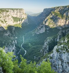 the valley is surrounded by mountains and green trees, with a river running between them