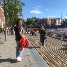 a man standing on top of a wooden walkway next to a river filled with people