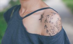 a woman with a flower tattoo on her shoulder and arm is looking at the camera