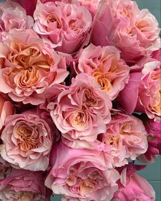 a bouquet of pink flowers sitting on top of a wooden table next to a blue wall