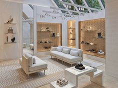 a living room filled with lots of white furniture and shelves full of shoes on display