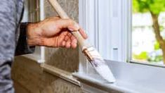 a person is holding a brush in their hand and cleaning the window sill outside