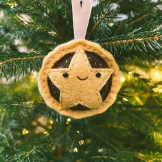 a felt ornament hanging from a christmas tree with a smiling face on it