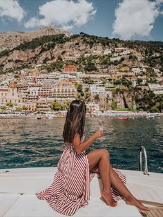 a woman sitting on the back of a boat looking at her cell phone in positi