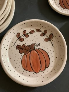 several plates with painted pumpkins on them sitting on a black tableclothed surface