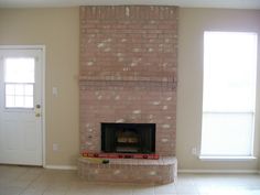 an empty living room with a brick fireplace