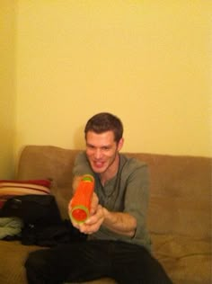 a man sitting on top of a couch holding an orange object