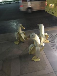 two yellow birds are on the sidewalk near a street light and a bus in the background