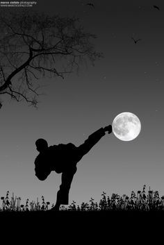 a person doing a handstand in front of a tree with the moon behind them