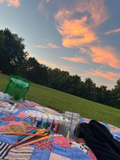 a quilted table cloth on the ground with paints and brushes