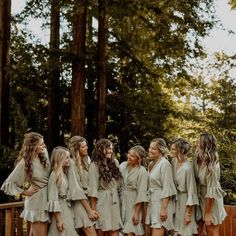 a group of women standing next to each other on top of a wooden deck in front of trees