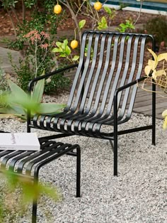 a metal chair sitting on top of a gravel covered ground next to a tree and bushes