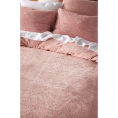 a bed with pink linens and white ruffles on the bottom, along with two pillows