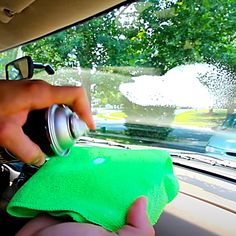 someone is cleaning their car windshield with a green towel and spray bottle in the back seat