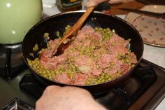 a person cooking food in a pan on the stove