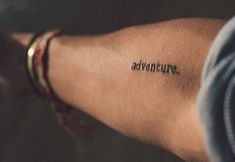 a person's arm with the word adventure written on it, in black ink