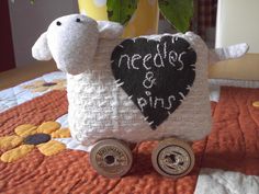 a stuffed sheep sitting on top of a bed next to a potted plant