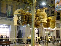 several wooden sculptures are hanging from the side of a pole in front of a building