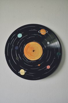 a black and yellow record with planets painted on it's side in the shape of a circle