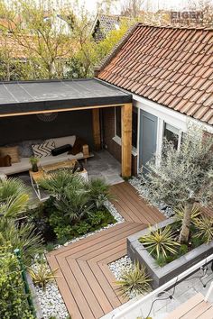 an outdoor living area with wooden decking and potted plants on the side of the house