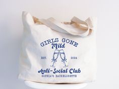 a white tote bag with the words girls gone mud and two champagne glasses on it