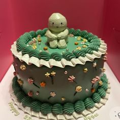 there is a cake decorated with green frosting and a small teddy bear on top