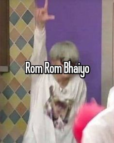 an old woman is standing in front of a purple wall with the words rom rom bhajjo on it